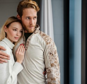 Beautiful young happy couple hugging and looking out window indoors